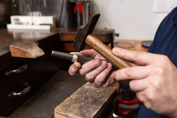 foreground, hammer hammering a silver ring to shape it in a jewelry workshop.