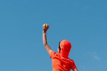 Kids sport tennis game concept. Boy child tennis player holding ball in his hand above his head...