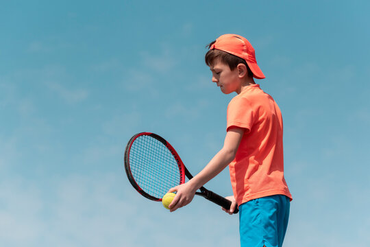 Child boy tennis player with racket and ball is focused and concentrated  prepares to serve ball in match. Kids sport tennis game. Sports physical  activity of children. Background copy space Stock Photo