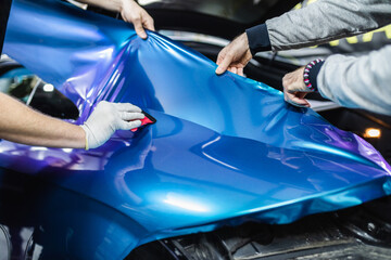 Car wrapping specialist putting vinyl foil or film on car. Selective focus.