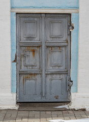 Heavy antique metal door with rust in the walls of a brick and concrete Gothic church. Unusual architecture.