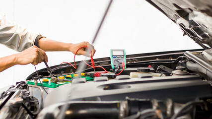 A technician is checking the car battery for availability.;