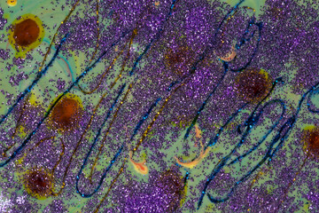 Purple sparkles and spots are scattered on a green acrylic background Abstract painting with curls. Popular fashionable art design.