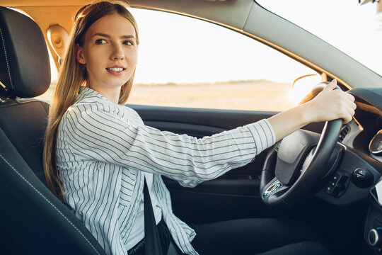 Young Happy Smiling Woman Driving Her New Car At Sunset