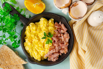 Skillet of scrambled eggs with bacon lardons for breakfast