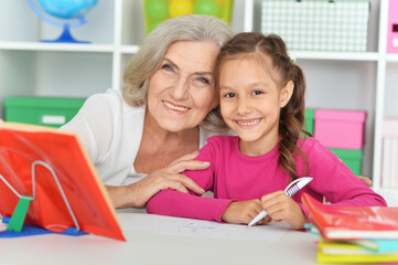 Portrait of grandmother and granddaughter doing homework together