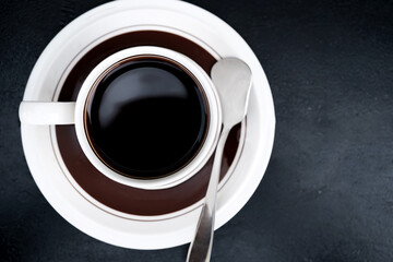 top view of morning hot black coffee cup on dark table with tea spoon