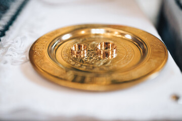 Wedding rings in the church. Wedding rings stand on glass box on table in church. Two golden wedding rings in a plate on the table at the ceremony before the wedding ceremony in the church