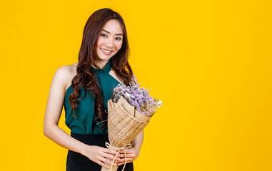 Cute and pretty curly hair Asian female brunette holding flower bouquet with cheerful and happy, studio shot isolated on bright yellow background.