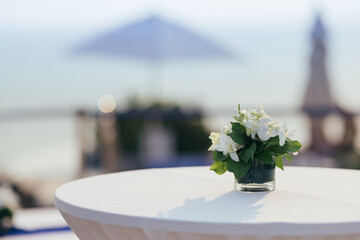 a glass vase with flowers on the white reception table at beachfront weddings party even