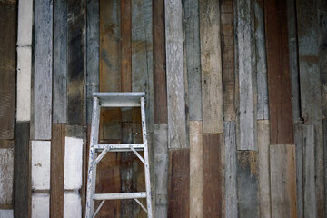old style dirty stainless steel ladder leaning against the old wood plank wall
