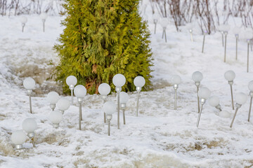 Eco-friendly energy-saving white solar-powered light bulbs on dirty melting snow
