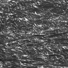 Crumpled dark plastic packing backdrop. Trash texture