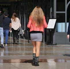 Fashionable woman walking in miniskirt and pantyhose in Duomo square, Milan, Lombardy, Italy.