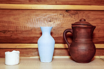 A white burnt-out candle. an earthenware jug. ceramic vase