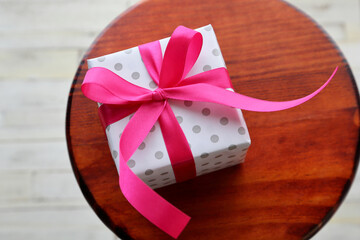 A gift of a pink ribbon wrapped in polka dot wrapping paper