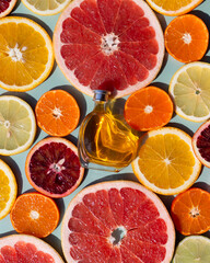 Vitamin C serum in a heart shaped bottle on a slised citrus set. Orange, grapefruit, lime, tangerine, lemon. Organic SPA cosmetics with orange oil.