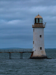 Fototapeta na wymiar white lighthouse in ocean with dark cloudy sky