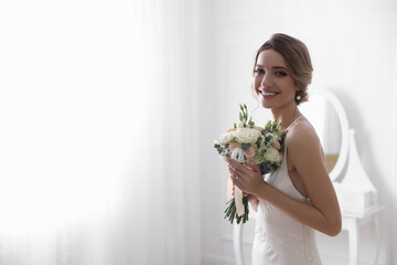 Bride in beautiful wedding dress with bouquet indoors. Space for text