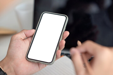 Mock up. Man hand holding a smartphone blank white screen at the office.