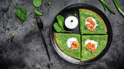 Green spinach crepes or pancakes with smoked salmon and sour cream. banner, menu, recipe, place for text