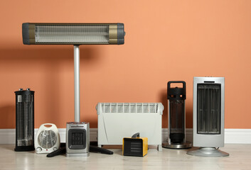 Different electric heaters near orange wall indoors