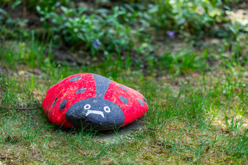 Handmade painted acrylic stone ladybug in garden