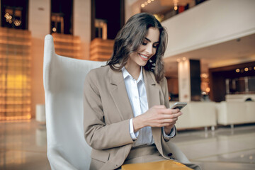 Fototapeta na wymiar Pretty businesswoman sitting and holding a smartphone in her hands