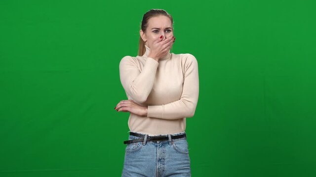 Young ill woman feeling nausea closing mouth with hands. Portrait of unwell sick Caucasian lady posing at green screen chromakey background. Pregnancy and food poisoning concept.