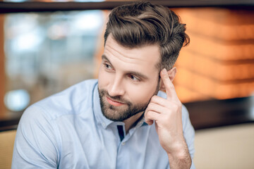Young bearded man sitting at the table and looking anticipated