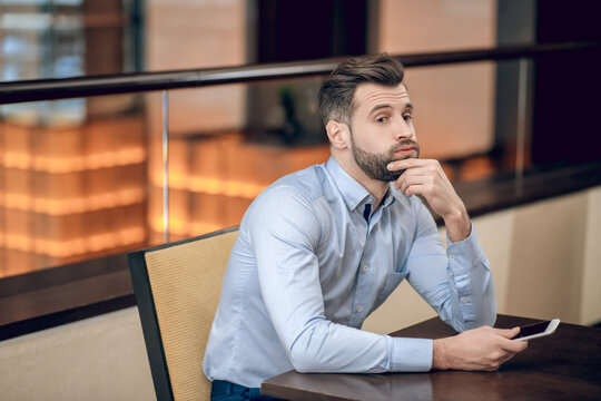 Young bearded man sitting at the table and waiting