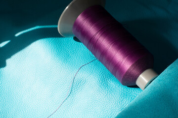 a spool of purple thread on a blue leather. Sewing thread. Shoe industry