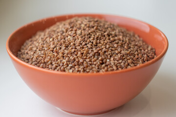 dry buckwheat in a brown bowl close-up