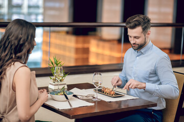 A couple having a dinner at the resaurant wjile sitting opposite each other