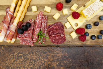 Meat and cheese plate antipasti snack with Prosciutto ham, Parmesan, Blue cheese, Cantaloupe melon and Olives on olive wood serving board