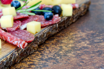 Meat and cheese plate antipasti snack with Prosciutto ham, Parmesan, Blue cheese, Cantaloupe melon and Olives on olive wood serving board