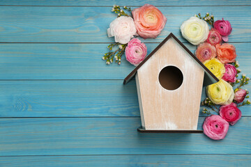 Stylish bird house and fresh eustomas on light blue wooden background, flat lay. Space for text