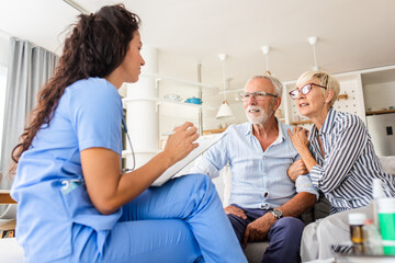 Female nurse talking to seniors patients while being in a home visit, senior couple signs an...