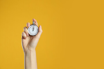 Woman holding vintage timer on yellow background, closeup. Space for text - obrazy, fototapety, plakaty