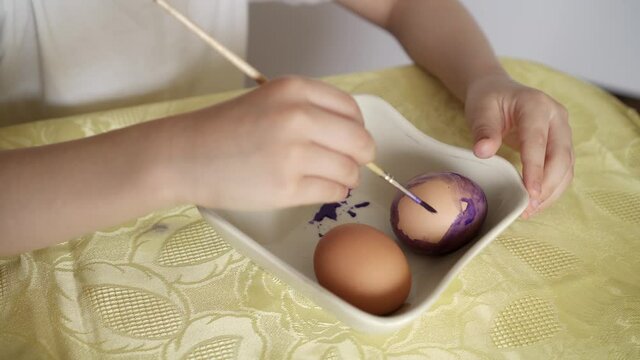 Happy Easter Holiday. Beautiful Caucasian kid boy paint and decorate eggs.