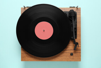 Modern turntable with vinyl record on light blue background, top view