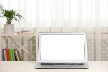 Modern laptop with blank screen on table at home