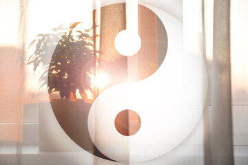 Plant on window sill behind curtain at home and  and Yin Yang symbol. Feng Shui philosophy - obrazy, fototapety, plakaty