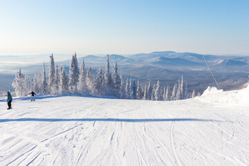 ski trail with snowy mountains and trees are covered with white fluffy snow in sunny day