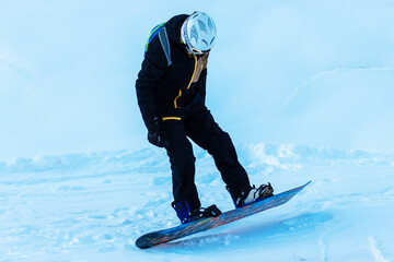 A snowboarder learns to ride a snowboard. He keeps his balance