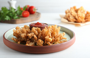 Delicious onion blossom with ketchup served on white wooden table