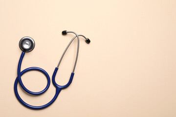 Stethoscope on beige background, top view. Space for text