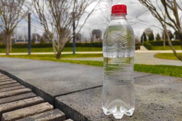 a water bottle with a red cap on the background of a modern park