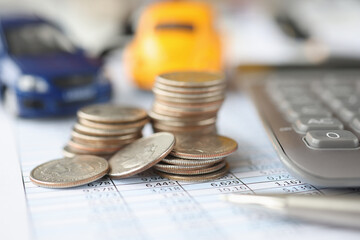 Calculator with money and toy cars are on table with numbers closeup