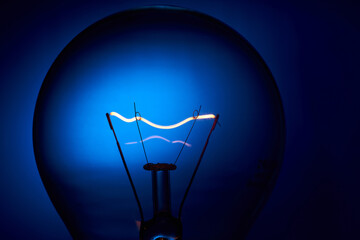 Electric bulb lamp with a spiral on a blue background